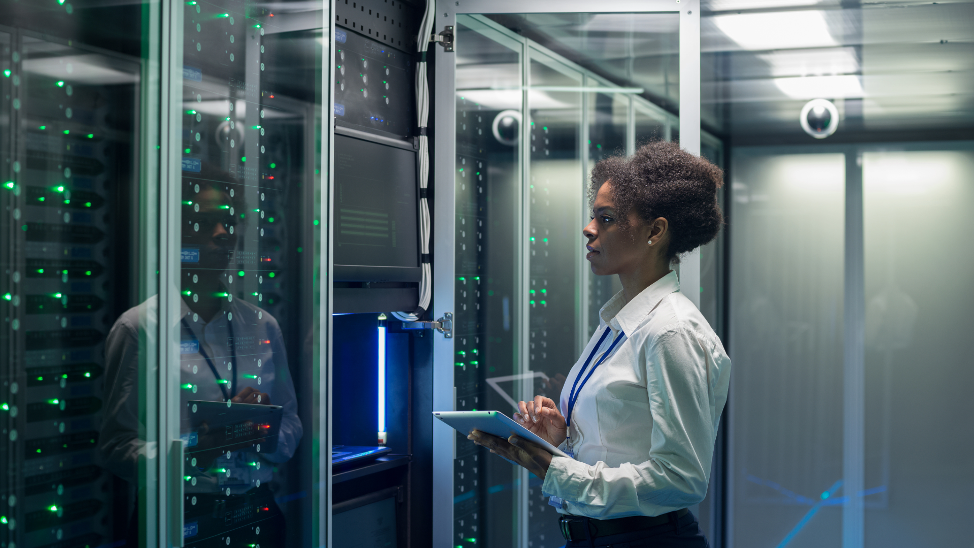 A woman in a business suit uses a tablet to check data center energy efficiency readings.