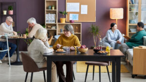A group of residents from an assisted living facility socialize in an activity room.