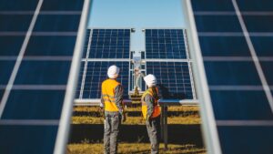 Two workers look at solar panels they installed to help a business earn a renewable energy certificate.